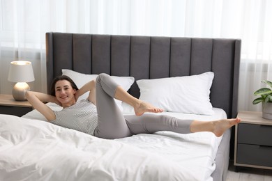 Photo of Young woman exercising on bed at home. Morning routine