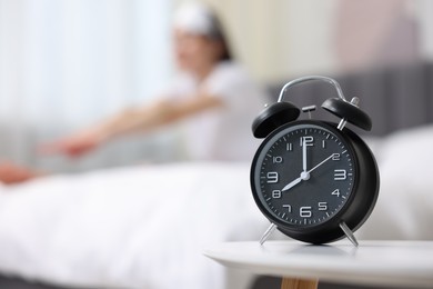 Young woman exercising on bed at home, focus on alarm clock. Morning routine