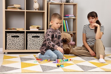 Psychologist observing little boy playing in autism treatment center