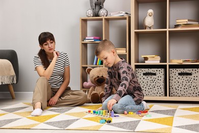 Photo of Psychologist observing little boy playing in autism treatment center