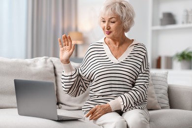 Photo of Beautiful grandmother having video chat via laptop at home