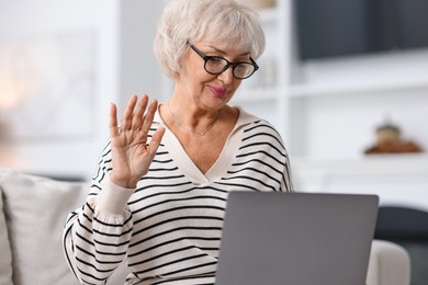 Photo of Beautiful grandmother having video chat via laptop at home