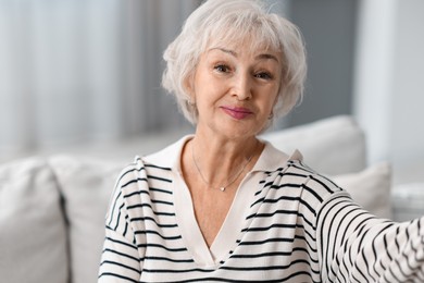 Grandmother with beautiful makeup taking selfie at home