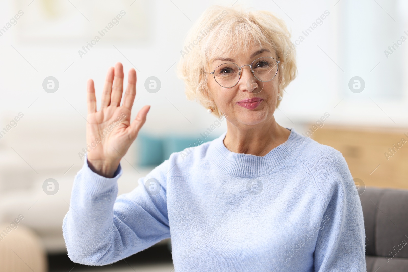 Photo of Portrait of beautiful grandmother waving hello at home