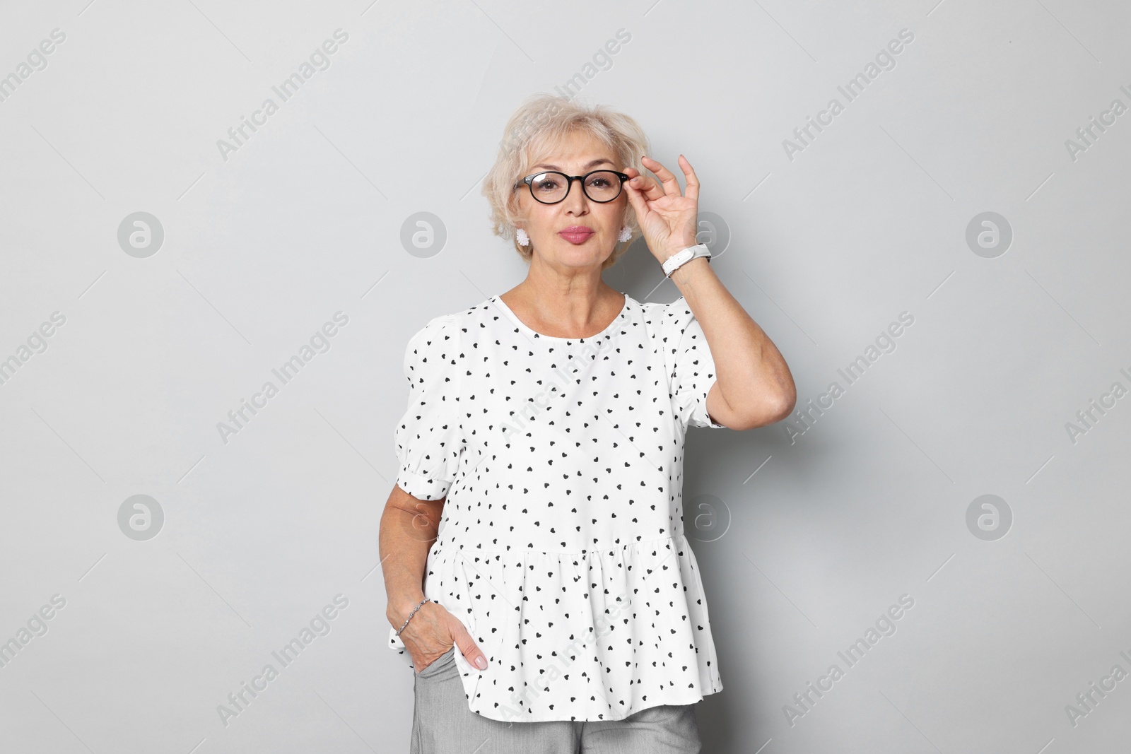 Photo of Portrait of elegant grandmother in glasses on light grey background