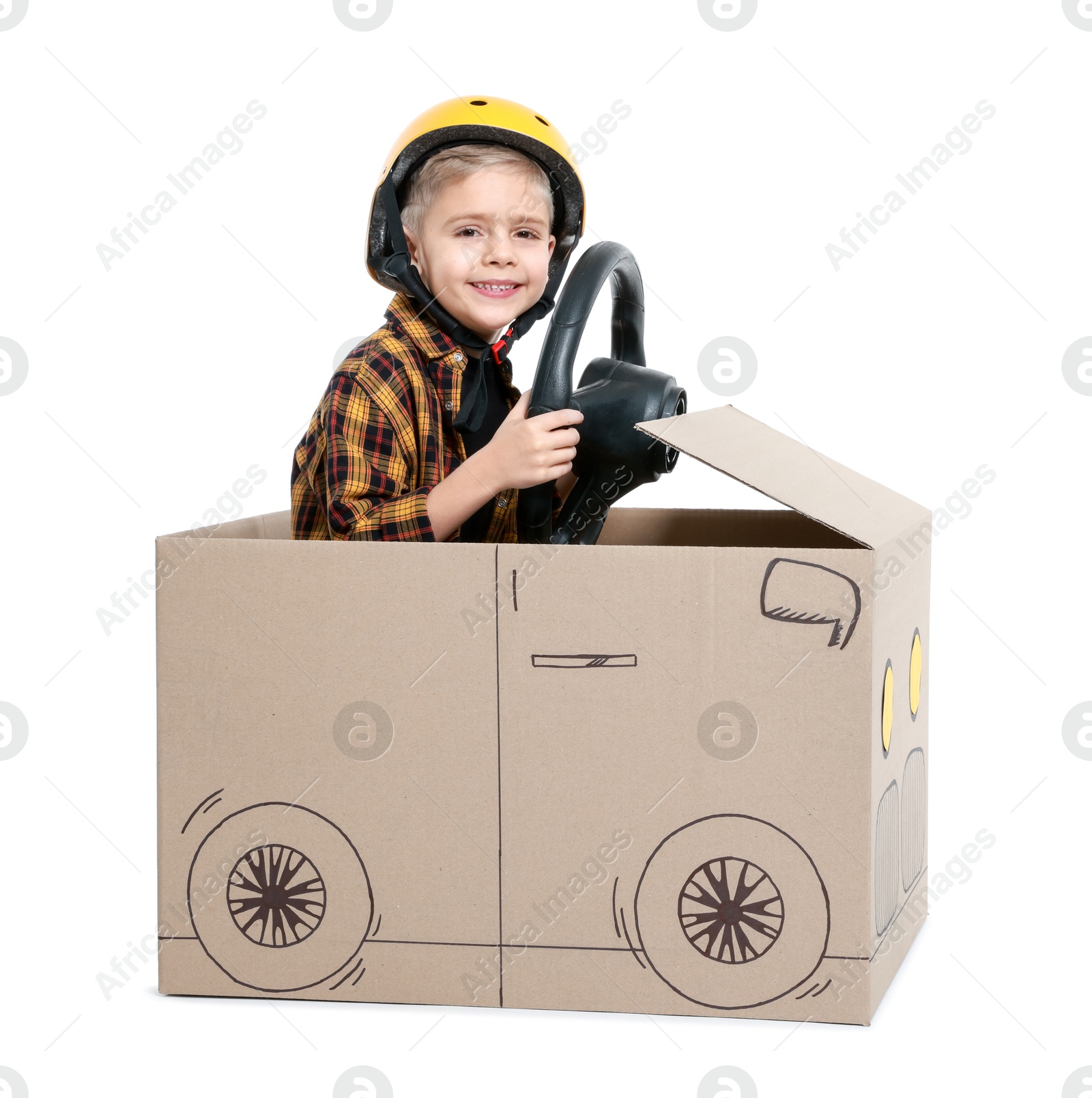 Photo of Little boy driving car made of cardboard on white background