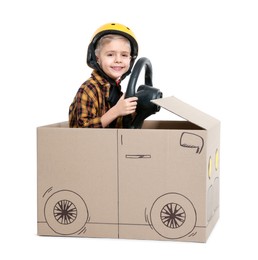 Photo of Little boy driving car made of cardboard on white background