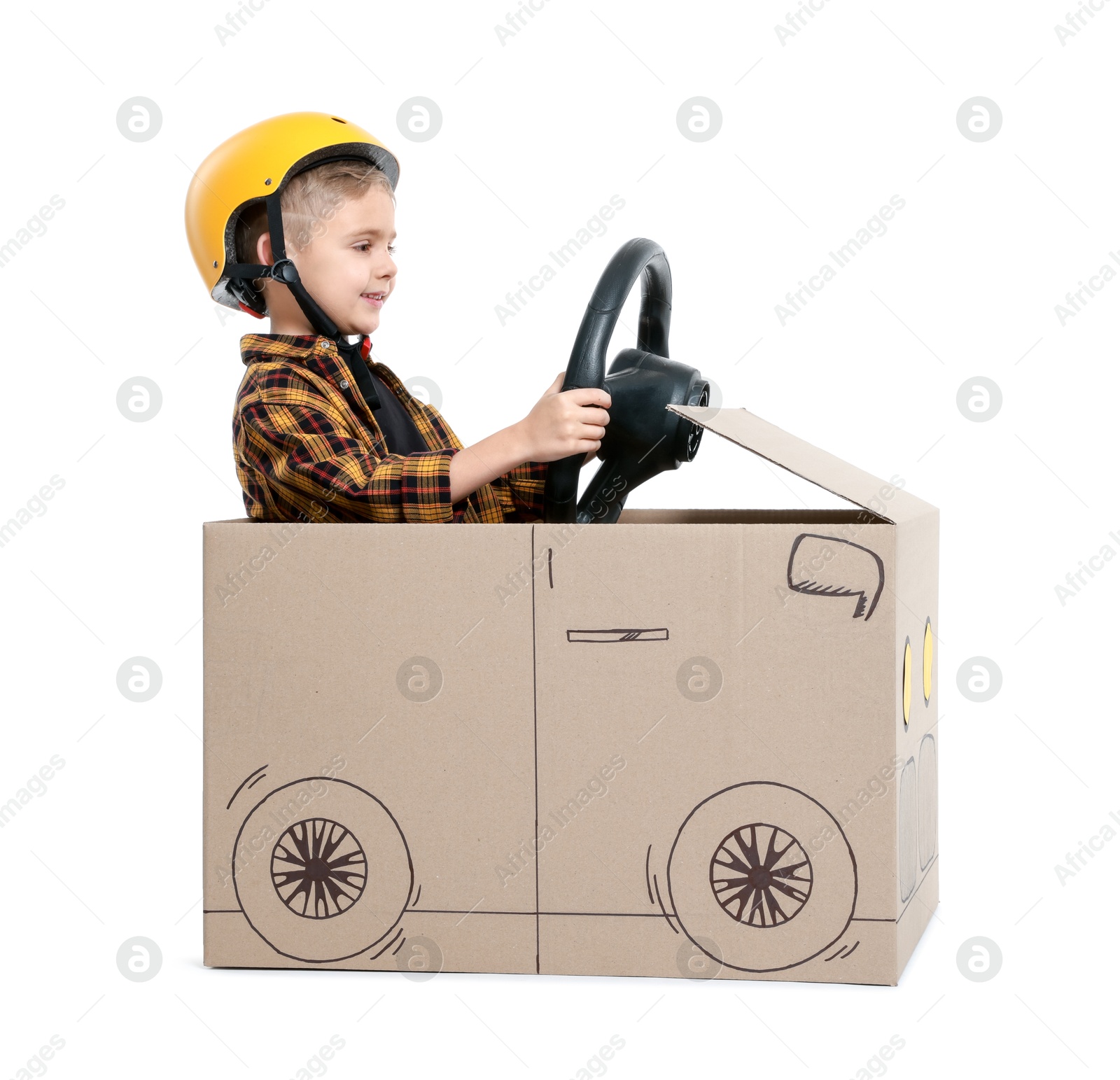 Photo of Little boy driving car made of cardboard on white background