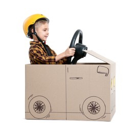 Photo of Little boy driving car made of cardboard on white background