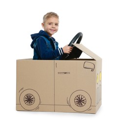 Photo of Little boy driving car made of cardboard on white background