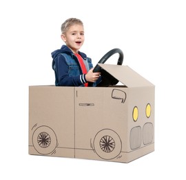 Photo of Little boy driving car made of cardboard on white background