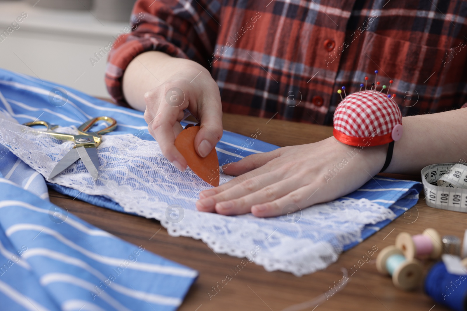 Photo of Woman working with cloth at wooden table, closeup