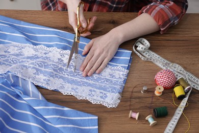 Photo of Woman cutting cloth at wooden table, top view