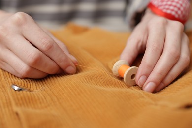 Photo of Woman with cloth and spool of sewing thread, closeup