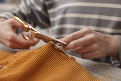 Photo of Woman cutting cloth at wooden table, closeup