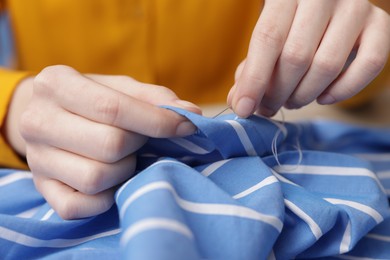 Photo of Woman sewing cloth with thread, closeup view