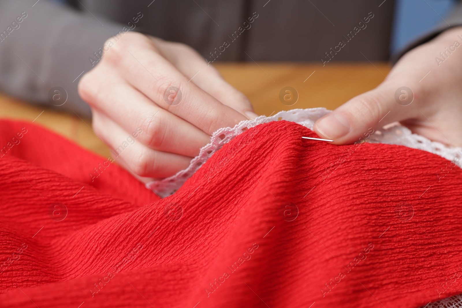 Photo of Woman sewing cloth with thread at table, closeup