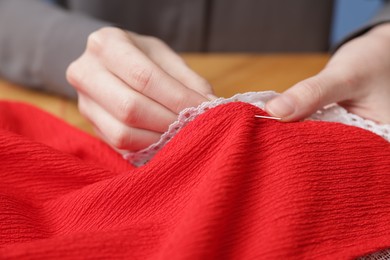 Photo of Woman sewing cloth with thread at table, closeup