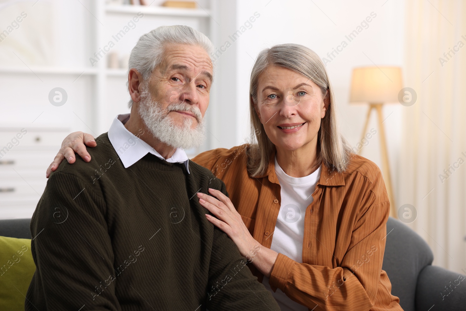 Photo of Portrait of happy elderly couple on sofa at home