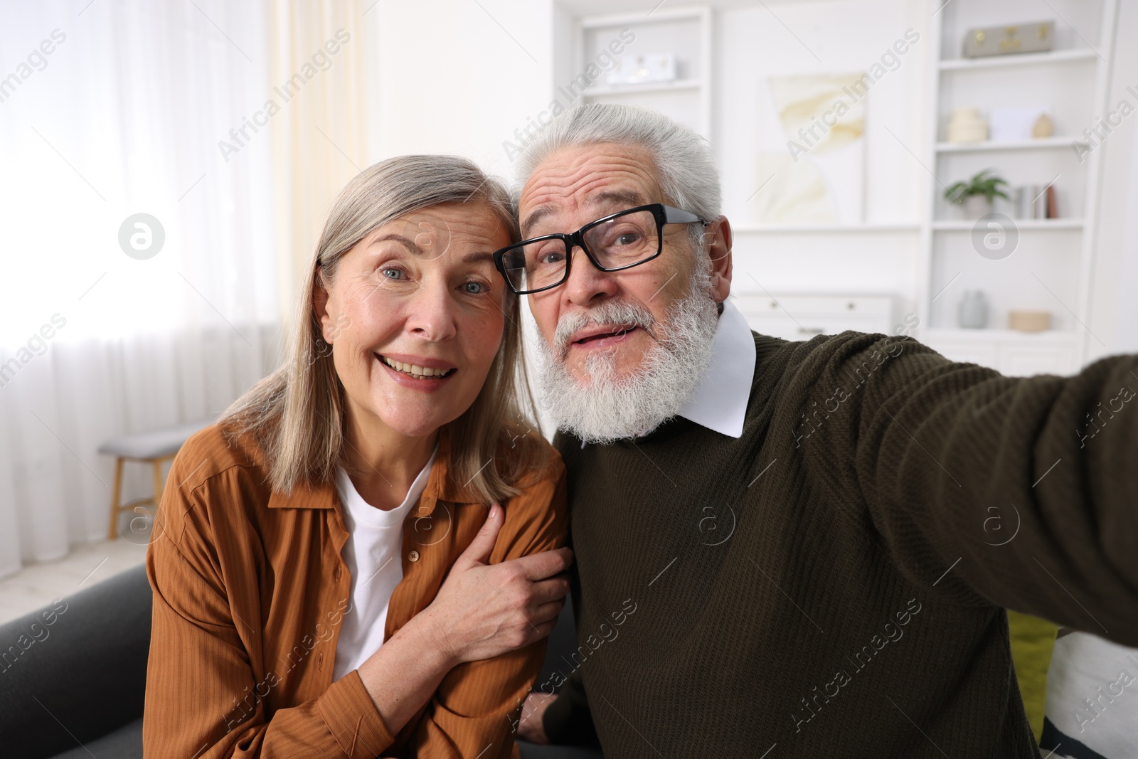 Photo of Happy elderly couple taking selfie at home