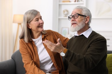 Happy elderly couple talking on sofa at home