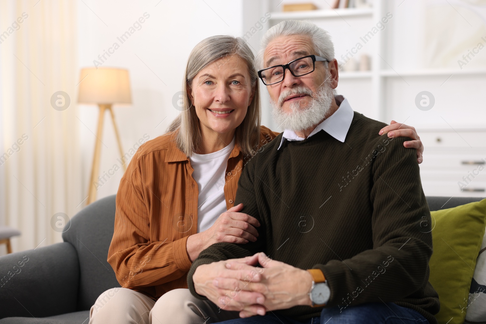 Photo of Portrait of happy elderly couple on sofa at home