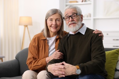 Photo of Portrait of happy elderly couple on sofa at home