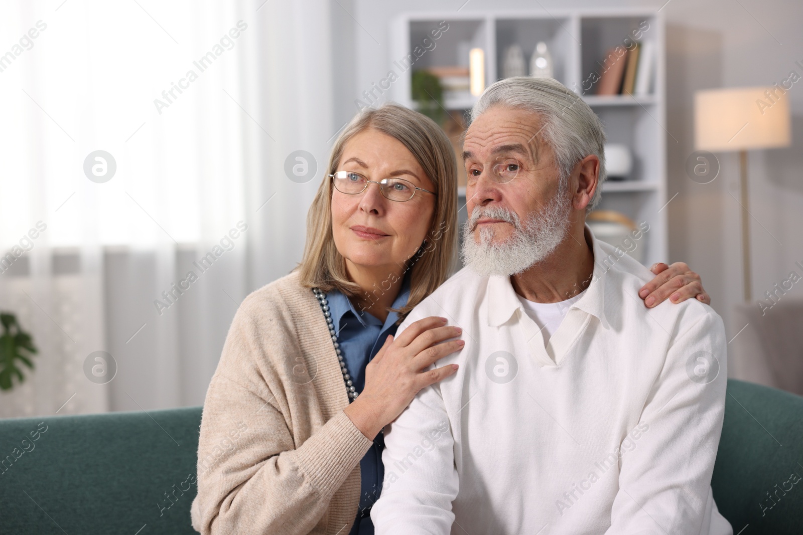 Photo of Cute elderly couple on sofa at home. Space for text