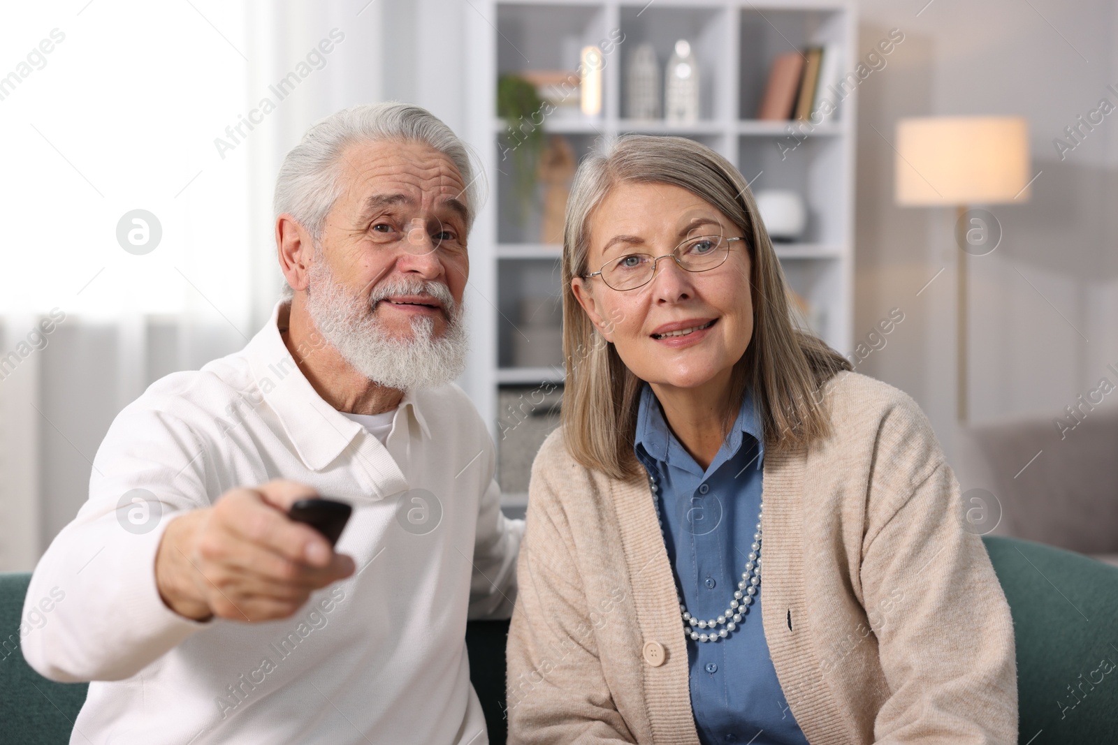 Photo of Happy elderly couple watching tv on sofa at home