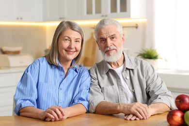 Photo of Portrait of happy elderly couple at table in kitchen