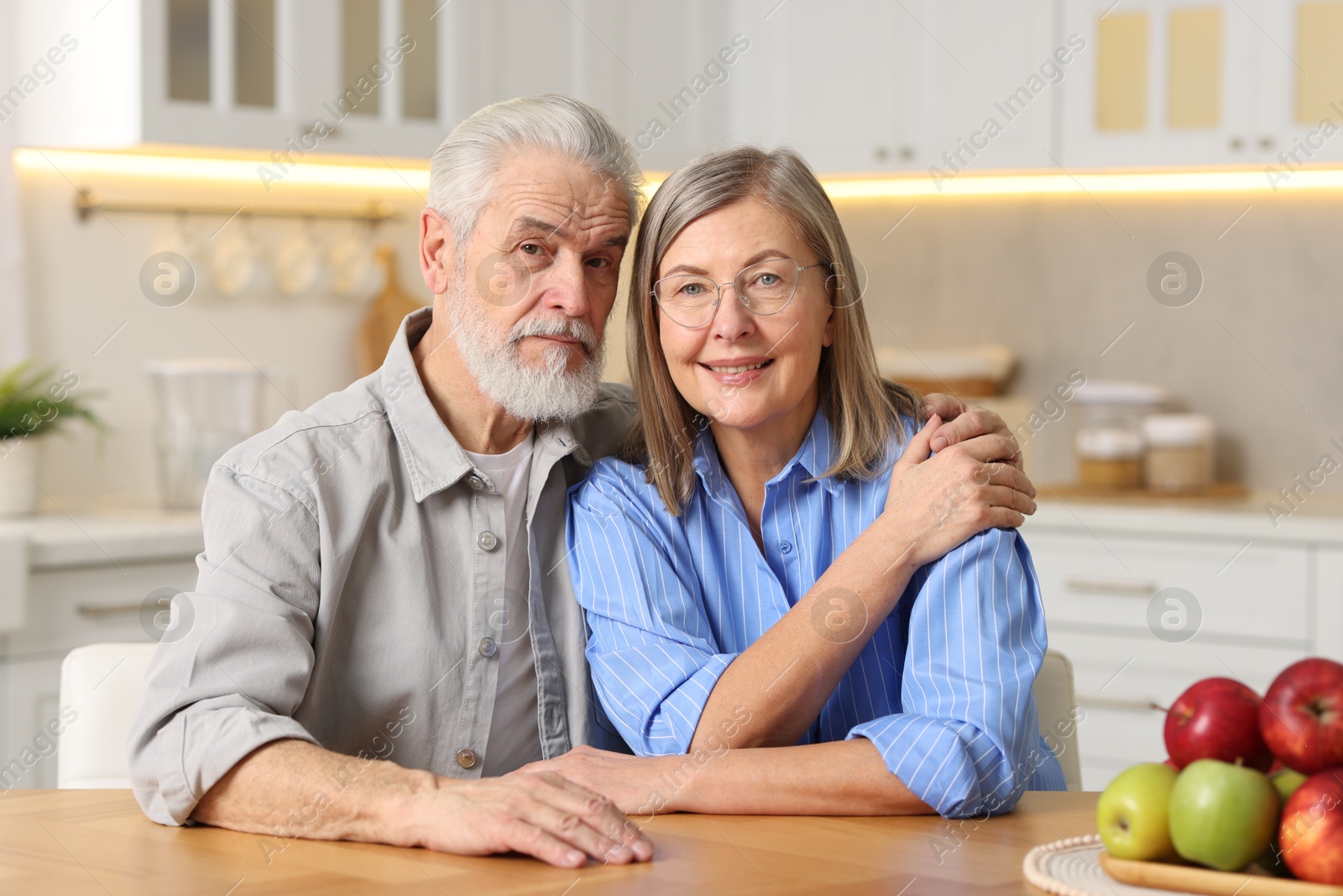 Photo of Portrait of cute elderly couple at table in kitchen