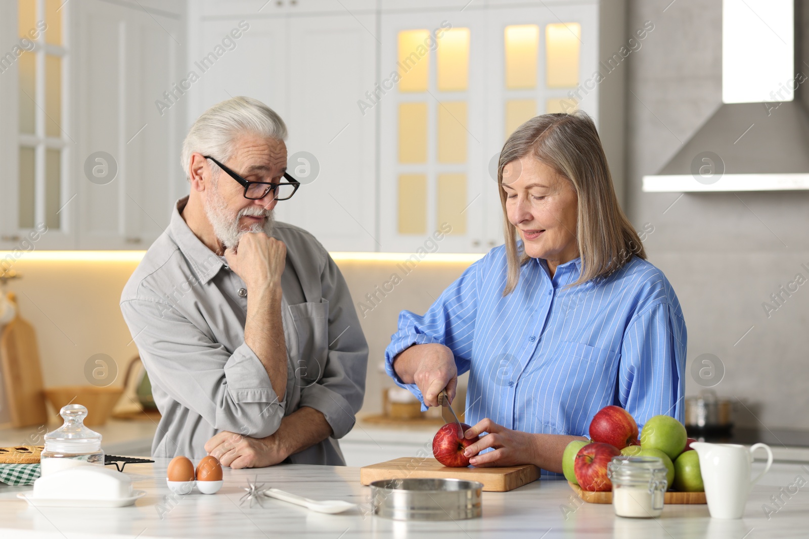 Photo of Cute elderly couple cooking together at table in kitchen