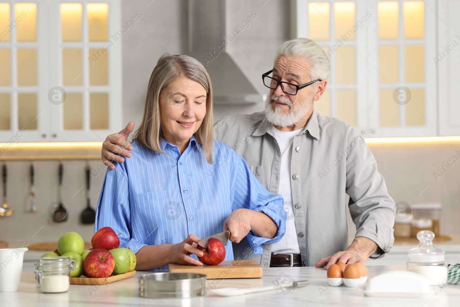 Photo of Cute elderly couple cooking together at table in kitchen