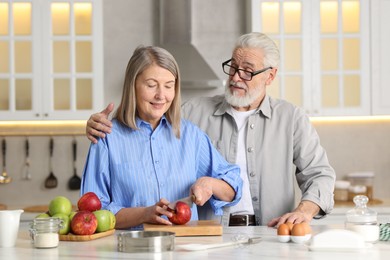 Photo of Cute elderly couple cooking together at table in kitchen