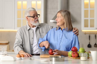 Cute elderly couple cooking together at table in kitchen