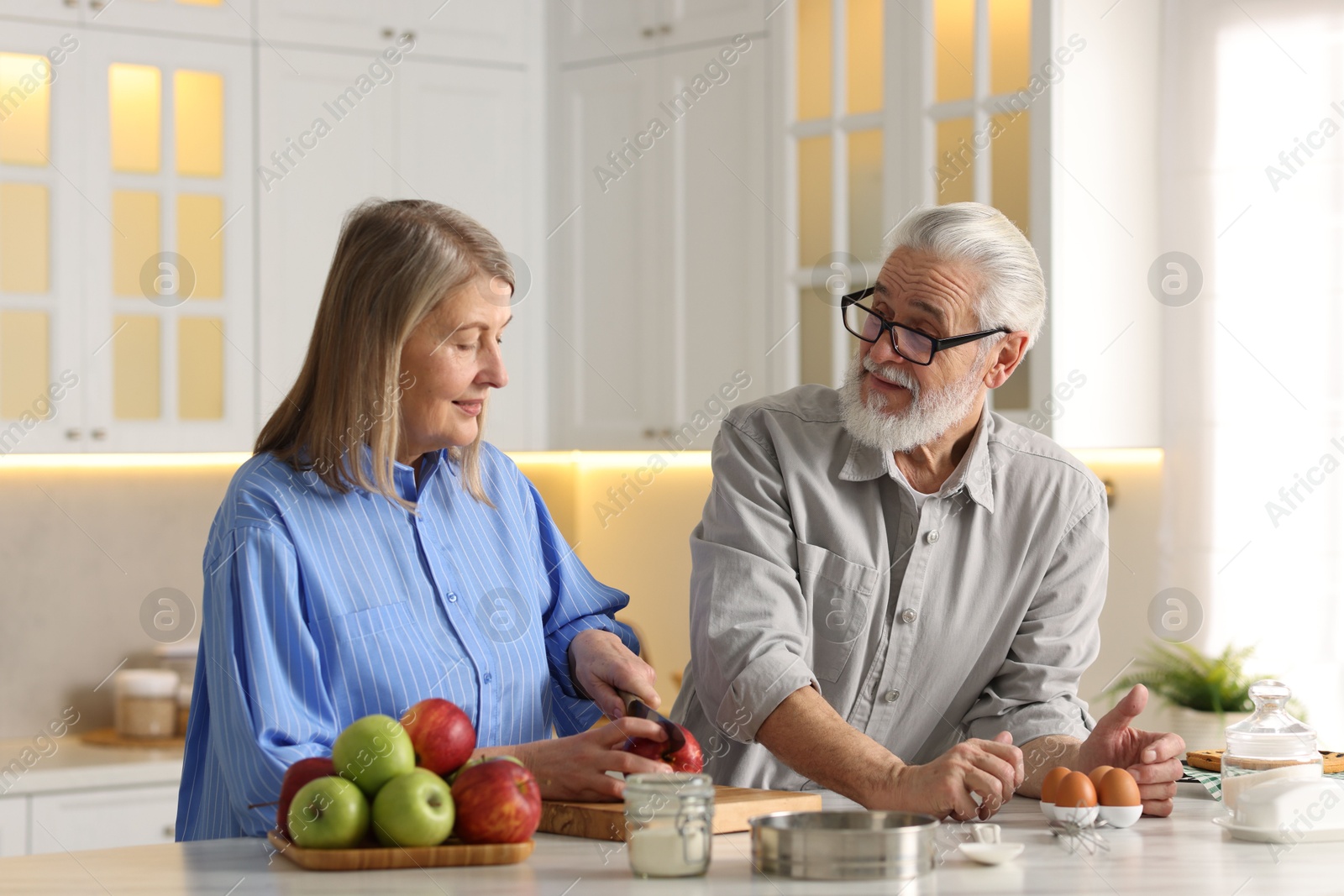 Photo of Cute elderly couple cooking together at table in kitchen