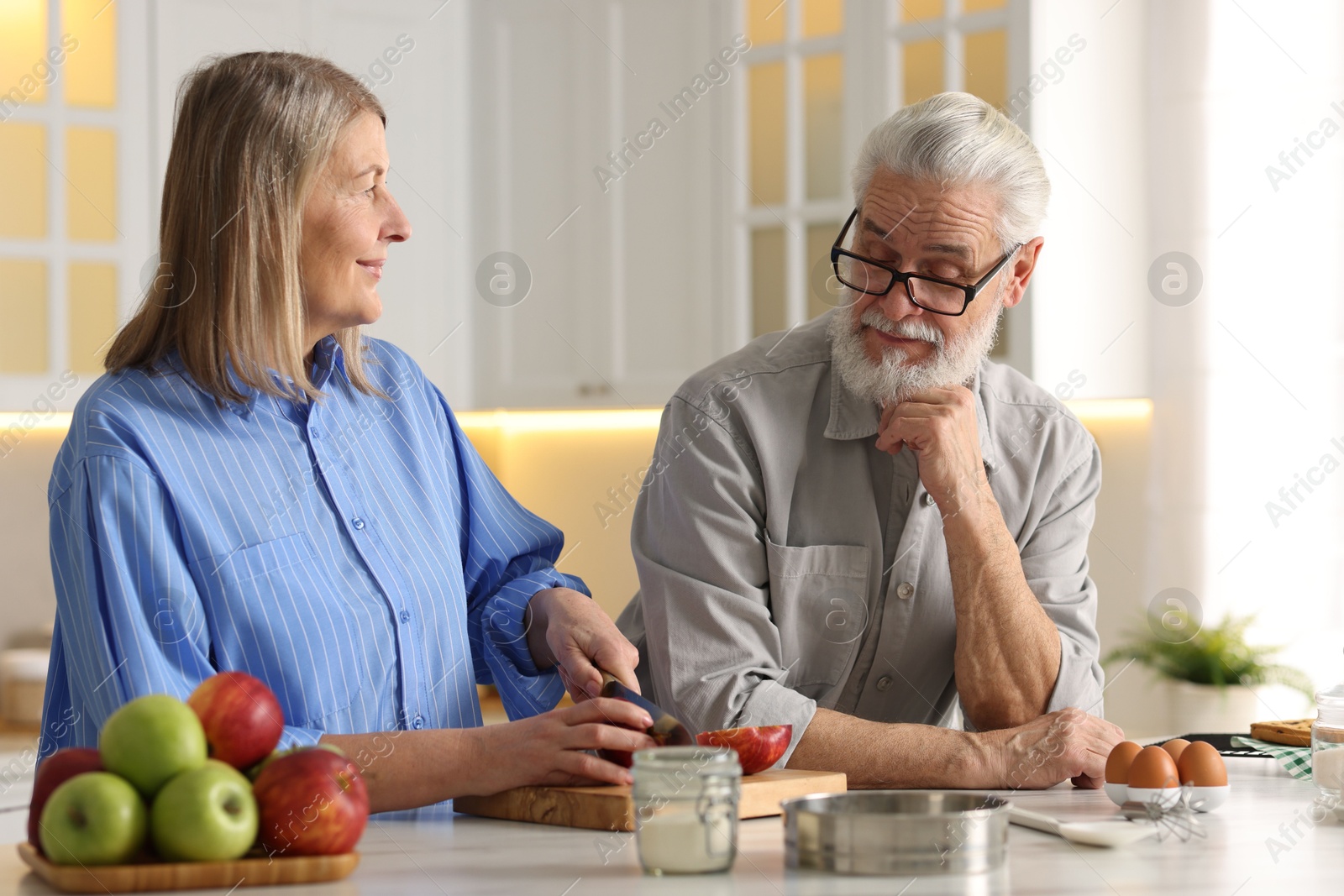 Photo of Cute elderly couple cooking together at table in kitchen