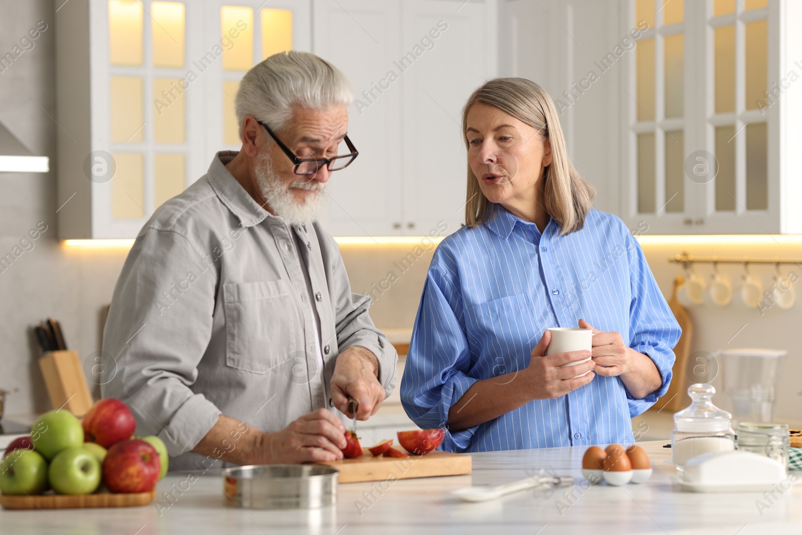 Photo of Cute elderly couple cooking together at table in kitchen