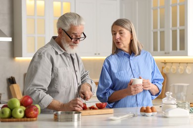 Cute elderly couple cooking together at table in kitchen