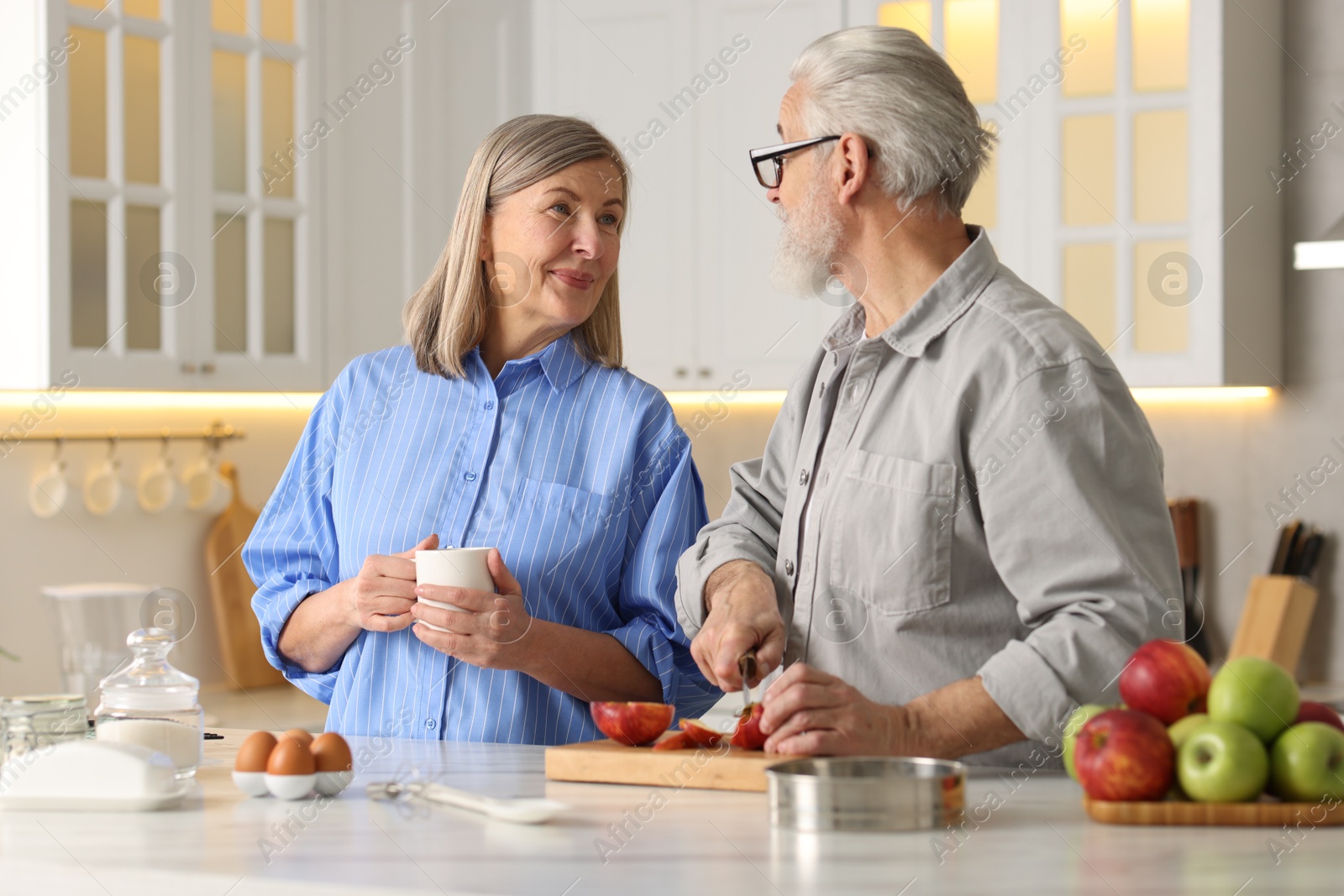 Photo of Cute elderly couple cooking together at table in kitchen