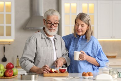 Photo of Cute elderly couple cooking together at table in kitchen