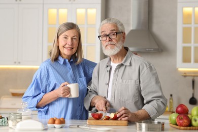 Photo of Cute elderly couple cooking together at table in kitchen