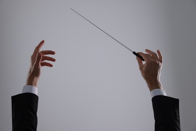 Professional conductor with baton on light grey background, closeup