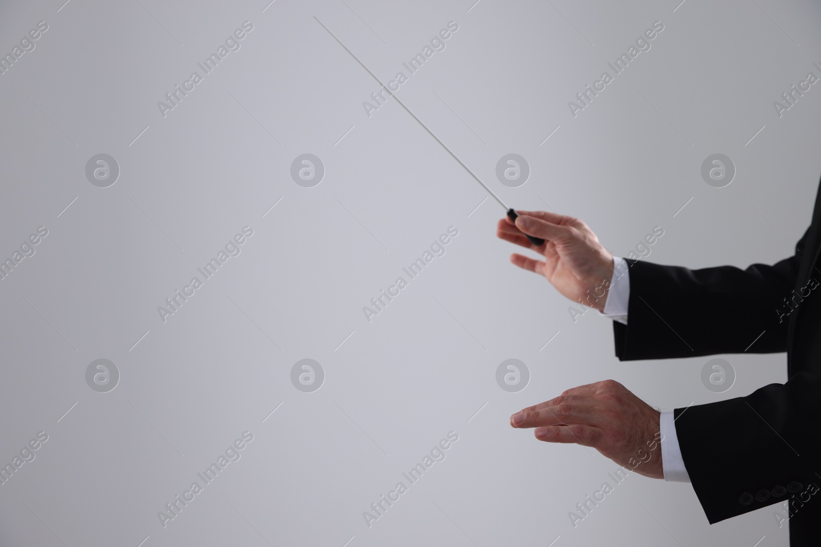 Photo of Professional conductor with baton on light grey background, closeup. Space for text