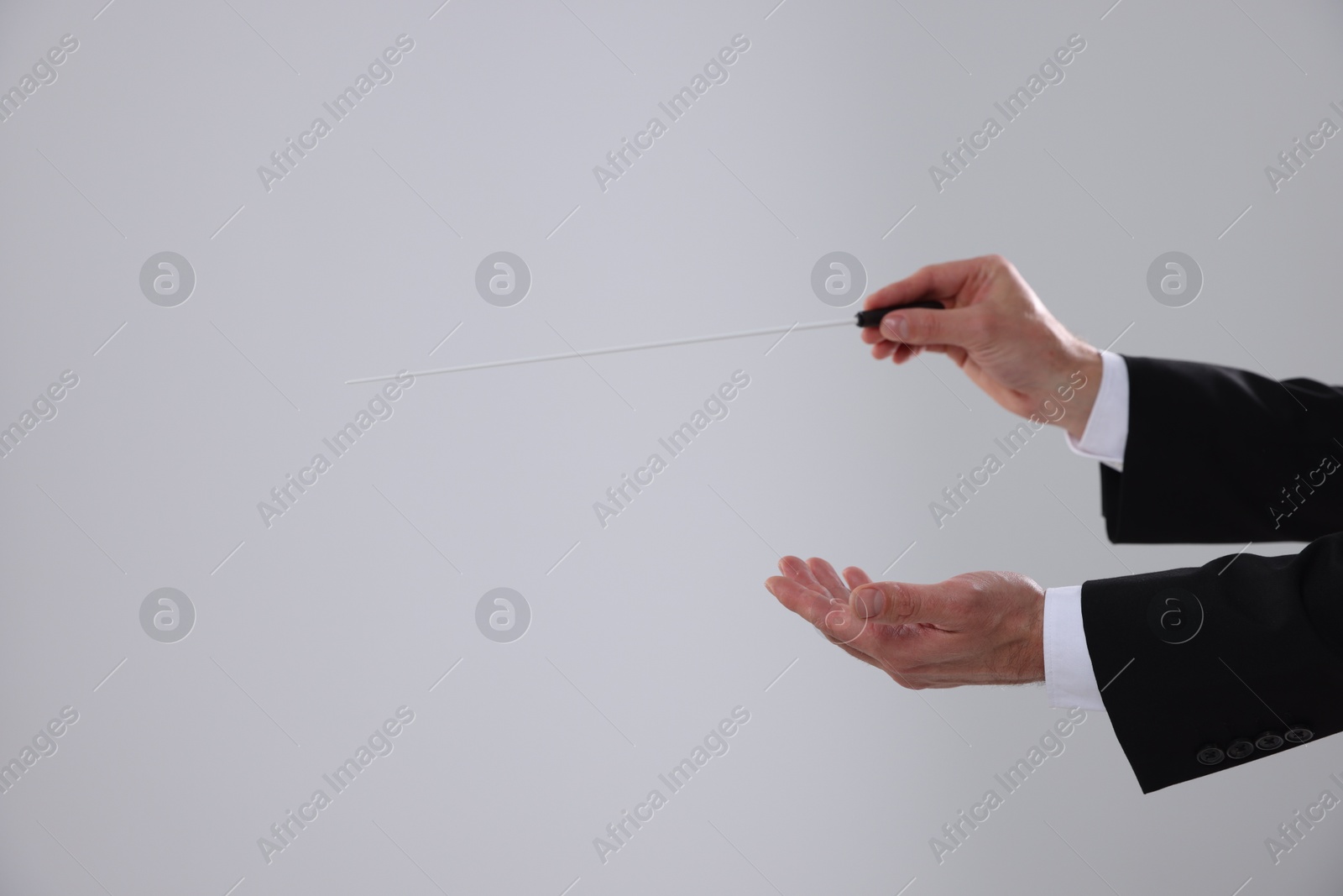 Photo of Professional conductor with baton on light grey background, closeup. Space for text