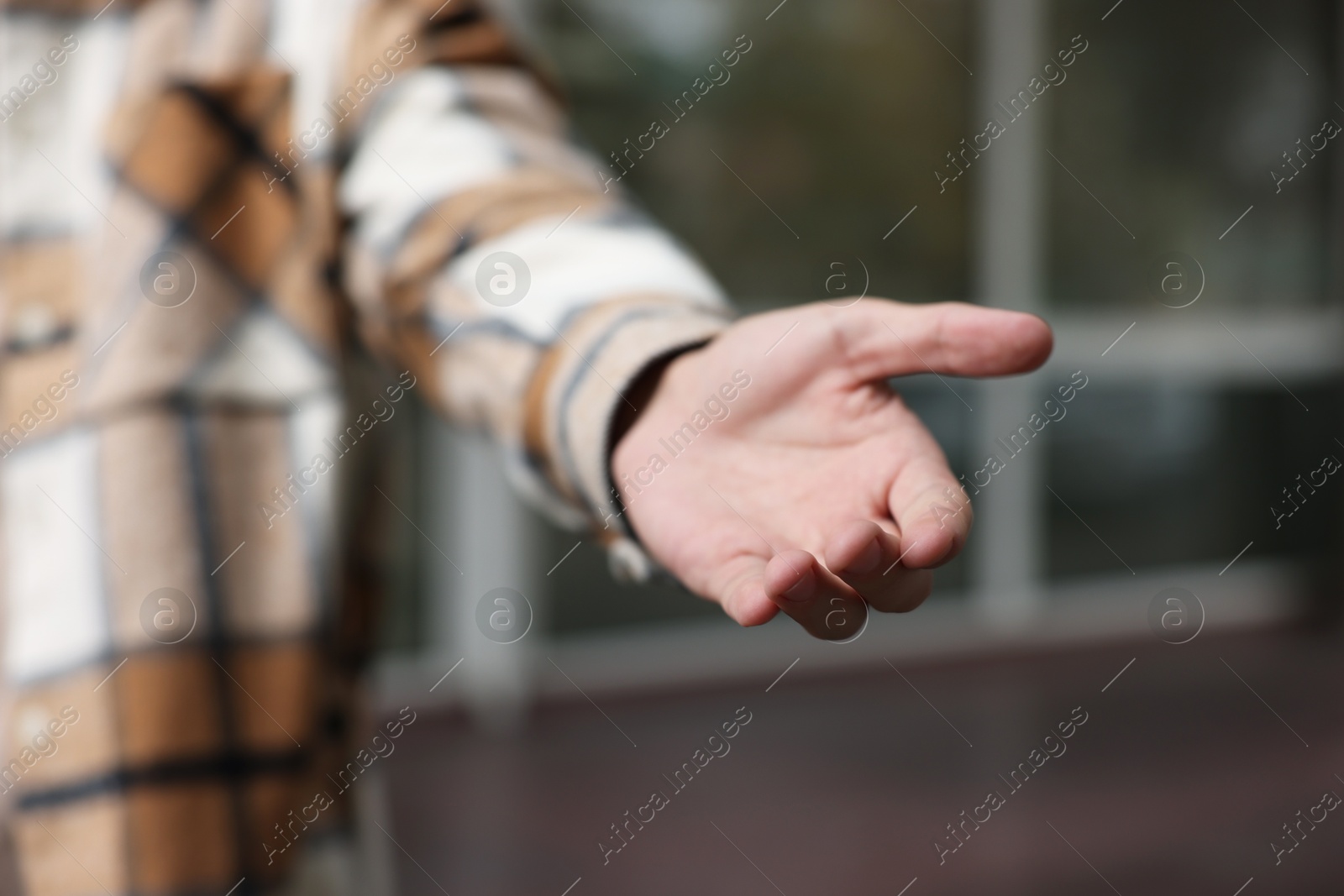 Photo of Offering help. Man reaching his hand outdoors, closeup