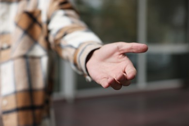 Offering help. Man reaching his hand outdoors, closeup