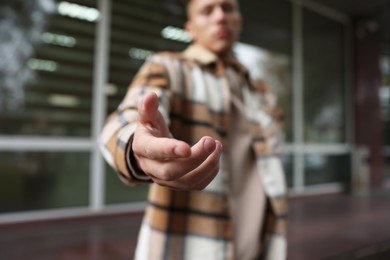 Photo of Offering help. Man reaching his hand outdoors, selective focus