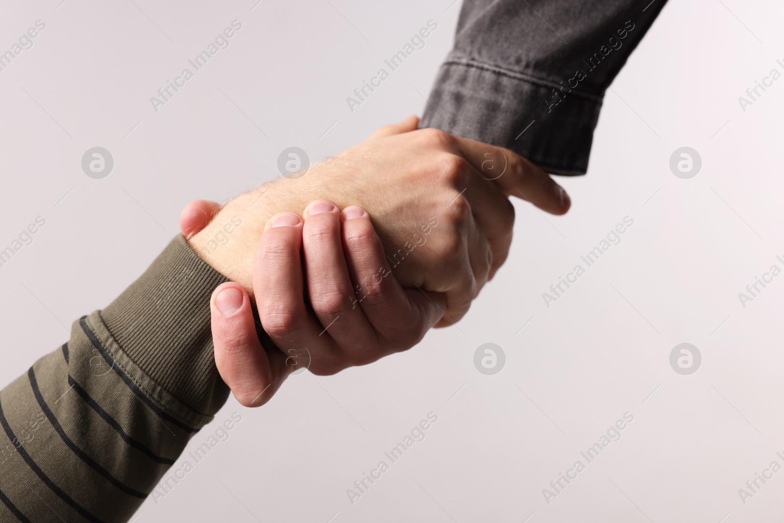 Photo of Help and support. People holding hands on light grey background, closeup