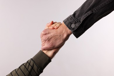 Photo of Help and support. People holding hands on light grey background, closeup